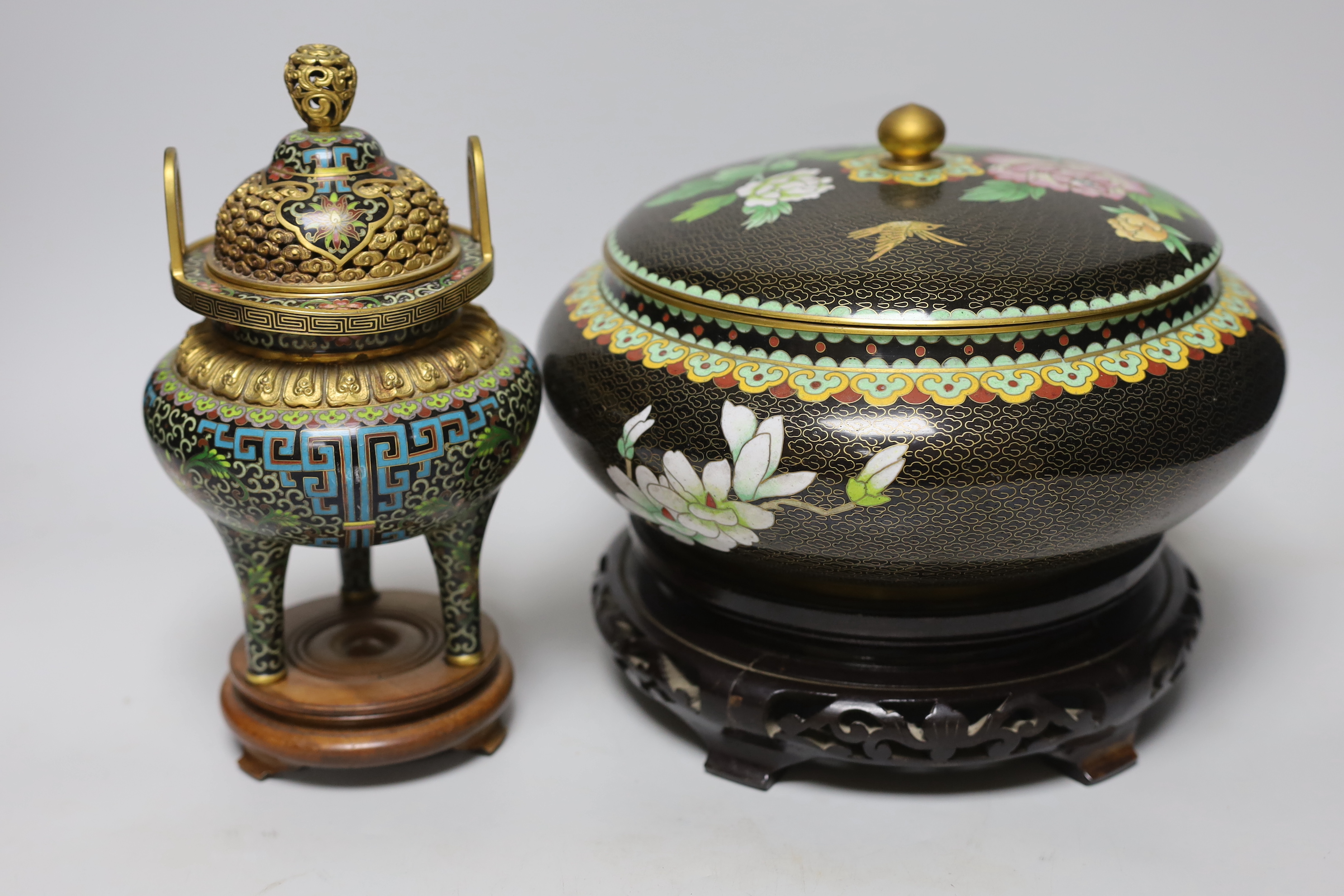 A Chinese cloisonné enamel three footed vase and cover together with a censer and cover, each raised on hardwood stands, the largest 26cm in diameter